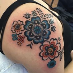 a close up of a woman's thigh with tattoos on it and flowers in the middle