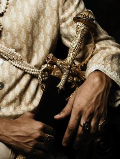 a close up of a person holding a cross and wearing pearls on their hands,