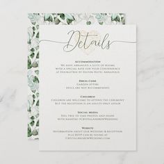 a white and green wedding menu card with gold foil lettering on the front, surrounded by greenery