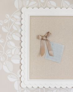 a white frame with a bow on top of it and a blue handkerchief in the middle