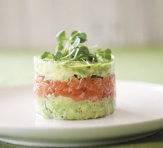 a white plate topped with a cucumber and salmon salad on top of lettuce