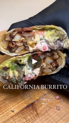 two burritos sitting on top of a wooden table next to a black glove