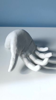 a hand that is sitting on top of a white surface with shadows coming from it