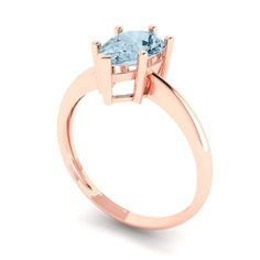 a rose gold ring with an aqua blue topazte stone in the center, on a white background