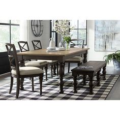 a dining room table and chairs in front of a window with black and white checkered rug