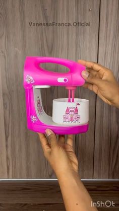 a person holding a pink and white toy hand mixer