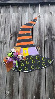 a paper witch's hat is hanging on the side of a wooden fence with halloween decorations