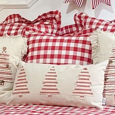 a red and white bed topped with pillows and christmas trees on it's covers