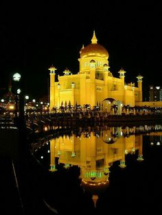 a large building lit up at night with lights reflecting in the water