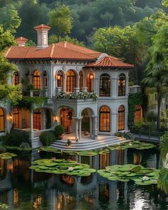 a large white house with water lilies in the front yard and trees around it