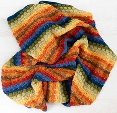 a multicolored knitted scarf laying on top of a white surface