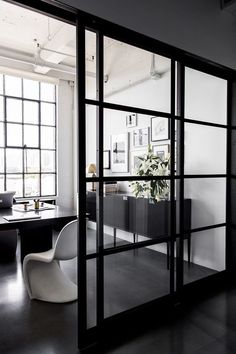 an office with black and white furniture and large glass doors that open up to the outside