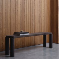 a book is sitting on top of a bench in front of a wooden wall and wood paneling