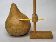 a small wooden object with a pencil sticking out of it's end next to a pear