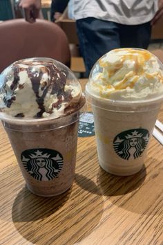 two starbucks drinks sitting on top of a wooden table