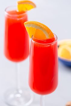 two glasses filled with red liquid and orange slices