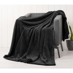 a couch covered in a black blanket next to a potted plant