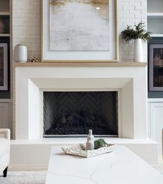 a living room with a white fireplace and pictures on the wall above it's mantle