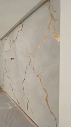 a bathroom with marble walls and gold trim on the shower wall, along with a toilet