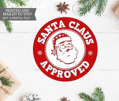 santa claus approved sticker on a white table with pine branches and presents around it