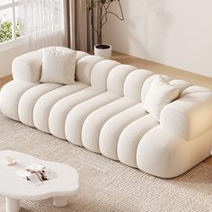 a large white couch sitting on top of a living room floor next to a window