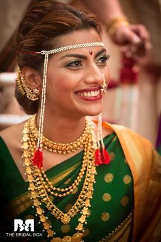 a woman in green and gold outfit with jewelry on her head, smiling at the camera