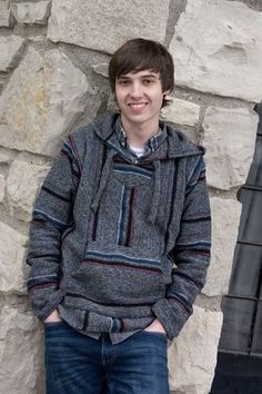 a young man standing in front of a stone wall