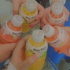 four children holding up bottles of liquid in their hands with the lid open and one child's hand reaching for it