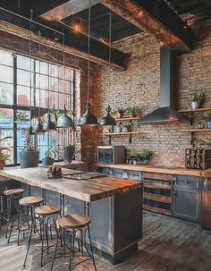 an industrial style kitchen with exposed brick walls and wooden flooring, potted plants on the island