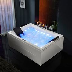 a white bath tub sitting next to a window with candles on top of the tub