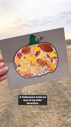 a person holding up a card with an image of a pumpkin and leaves on it