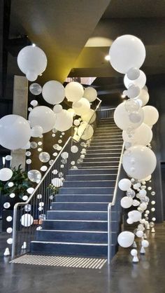 some white balloons are hanging from the stairs