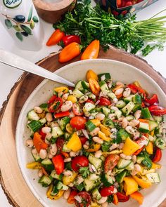 a white bowl filled with vegetables on top of a wooden plate next to a spoon