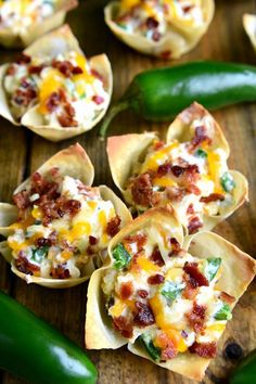 small shells filled with food sitting on top of a wooden table next to green peppers