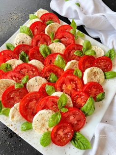 tomatoes, mozzarella and basil on a cutting board with white towels in the background