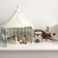 a white shelf topped with toys on top of a wooden table next to a tent