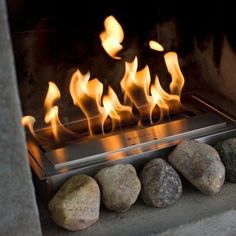 a fireplace with rocks and flames burning in it