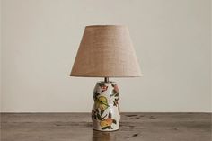 a lamp that is sitting on top of a wooden table with a linen shade over it