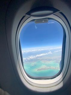 an airplane window looking out at the ocean and land from inside it's plane