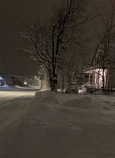 a snow covered street at night with houses in the background