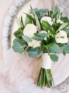 a bouquet of white flowers and greenery on a plate