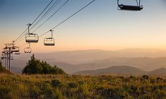 the sun is setting over mountains and hills as a ski lift goes up in the sky