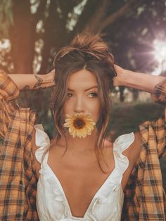 a woman with a flower in her mouth is holding her hair up to her face