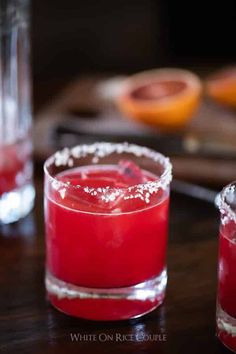 two glasses filled with red liquid sitting on top of a table