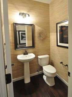 a white toilet sitting next to a sink in a bathroom under a framed painting on the wall