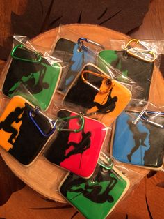 six keychains with different colored silhouettes are on a wooden tray and one is in the shape of a horse