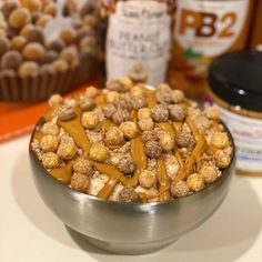 a metal bowl filled with peanut butter and pretzels next to some other snacks