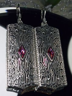 "Earrings Description Made To Order Inspired by the Art Deco movement of the 1920s and 30's, I now offer these lovely Antique reproduction earrings in sterling silver (Recast from an Art Deco pin). Each stunning 1ct flawless Man-made/Simulated Red Ruby gemstone is 8mm long by 4mm in width. The gemstones have perfect color and clarity. The earrings are 2 1/8th inches long and 9/16th\" at their widest point. Notice the beautiful design of the Deco filigree setting. A gift box is included and all i Ornate Red Filigree Earrings, Ornate Red Earrings For Party, Red Filigree Drop Earrings, Red Filigree Dangle Earrings, Ornate Red Earrings For Formal Occasions, Red Victorian Jewelry For Evening, Ornate Handmade Evening Earrings, Vintage Red Pierced Earrings, Handmade Ornate Earrings For Evening