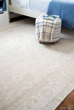 a bedroom area with a bed, chair and rug on the floor in front of it