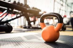 an orange kettle sitting on top of a mat in front of a gym equipment rack